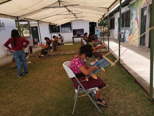 Figure 1 Group of young women learning to weave on backstrap looms during the pandemic as part of the scholarship programme Connecting with Your Roots co-ordinated by Ixchel Museum, Guatemala with support of Ibermuseums.Footnote7 Photograph courtesy of Ibermuseums, Citation2021.