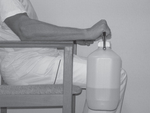 Figure 2. Photograph showing exercise set-up with the patient seated in an armchair with forearm support, holding the weight (a plastic container with a specified amount of water in it) in the affected arm, and performing exercise by lifting and lowering the container.