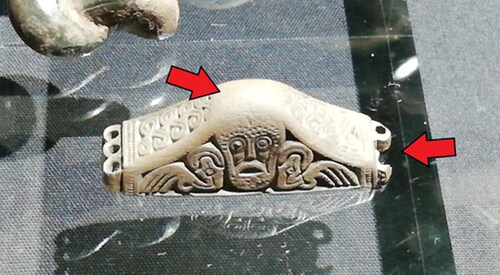 FIG 2 Pommel 68 from the Staffordshire Hoard. Arrows (added by author) highlighting extensive abrasion and damage (scale: 49 mm × 16 mm × 18 mm). Photograph courtesy of Howard Williams.