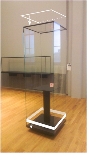 Figure 5. Photograph showing elegant design of a freestanding showcase with hinged door, transparent silicone door gasket, powder coated bottom deck, and support table. The white arrows indicate the locations where the structural adhesive Terostat-9220 is applied; the adhesive connects the glass windows with metal parts in the top and bottom.