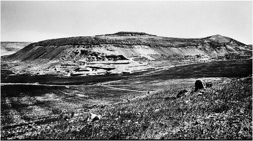 Figure 4. The ‘Revetment’, excavated around the entire site, appears as a dark line on the mid-slope of the tel: the northern side on the left and the western side on the right (looking east) (Starkey Citation1933, Pl. I, courtesy of the Wellcome Trust archive, London).