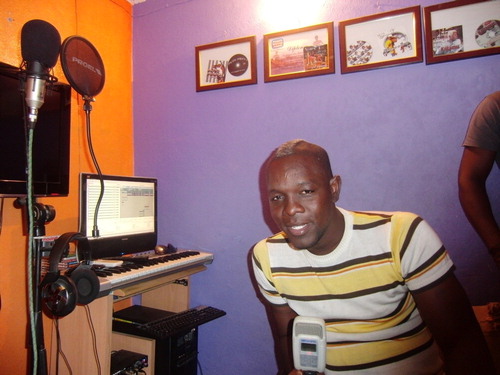 Figure 2 DJ Killamu at his studio Guetto Produções, Rangel (Luanda), 2012. To the left computer cum keyboard controller for music production and microphone with headphones for vocal capture. Diplomas, prizes for particular CD releases, in background. Photo by the author.