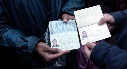 Figure 4. Ai and Mahmoud playfully exchange passports in front of the camera and a group of onlookers.
