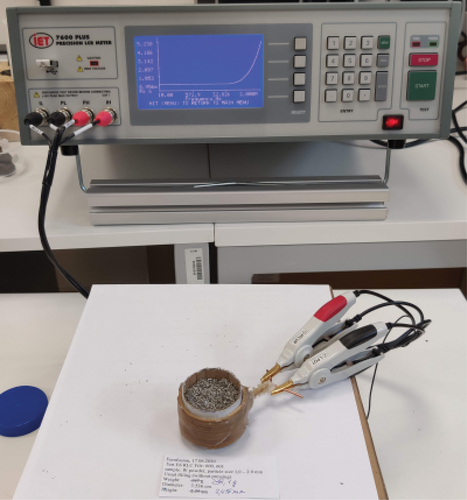 Fig. 1. Measuring the electrical parameters of the cell. The test material (the load) is W dust, and the measuring inductor is coiled around the sample.