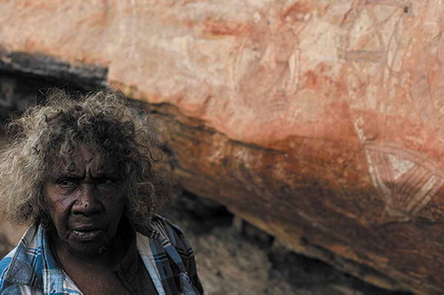 Fig. 3. Josie Gumbuwa Maralngurra at the Nanguluwurr rock art site, Kakadu. In the background a turtle and barramundi painted by her father Djimongurr in 1964. Photograph by Iain Johnston, 2019.