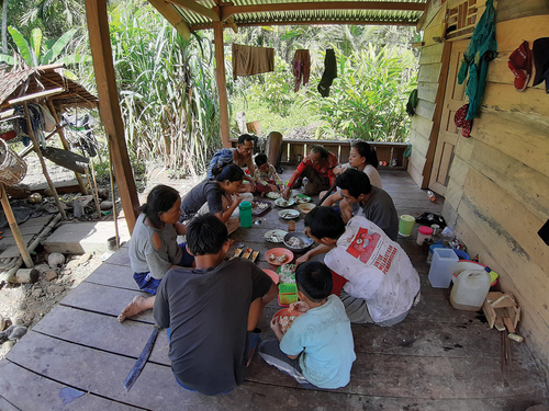 Figure 6. A typical family meal. People gather together in a circle enjoy taro dumpling (subbet), roasted sago and steamed fish in bamboo tubes.