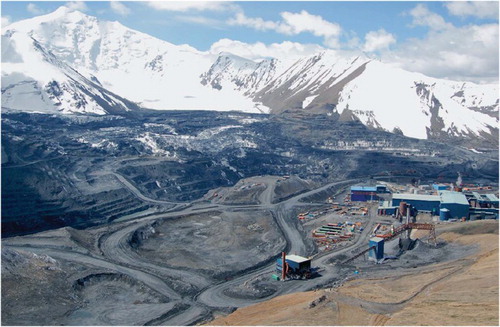 Figure 2. View southwards across the mine in June 2012, showing the alpine terrain and the appearance of glacier ice in the upper terraces on the pit wall where the Davidov Glacier is being excavated (image from CitationThalenhorst et al., 2012).