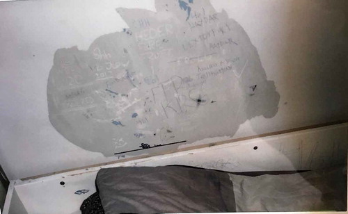 Photo 4. Photo taken by a young male showing the bed and a partially destroyed wall with doodles on it