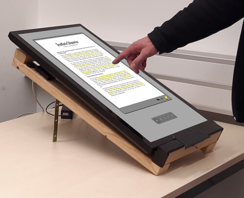 Figure 1. Re-enactment of a participant standing in front of the height-adjustable table with the inclined display on which the documents were presented.