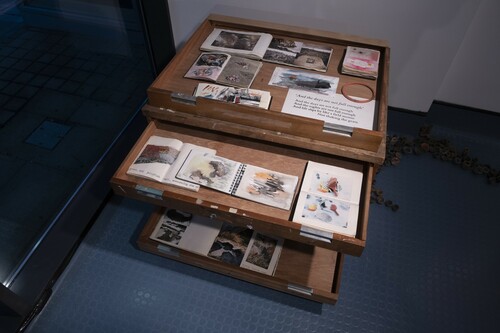 Figure 5. Sally Madge’s sketch books arranged in an appropriated plan chest, © Amy Madge and Lucy Madge, Photo: Colin Davison.Plan chests are both agents of storage and structures designed for observation, and so using the horizonal plane of drawers and top, we arranged the sketchpads to survey and look for emblematic themes and to table recurrent ideas