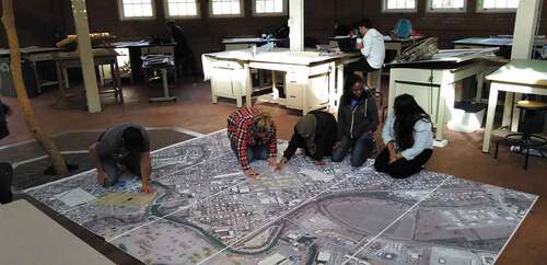 Figure 3. Student collaboration on a big map layered on the floor for project reconciliation.