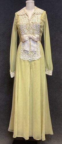 Figure 6 Luis Estévez, yellow evening jumpsuit, full front view, fabric, lace, and metal, ca. 1975, ISU Textiles and Clothing Museum, 2022.7.10. Photograph by authors. <https://tcm.catalogaccess.com/objects/11344>