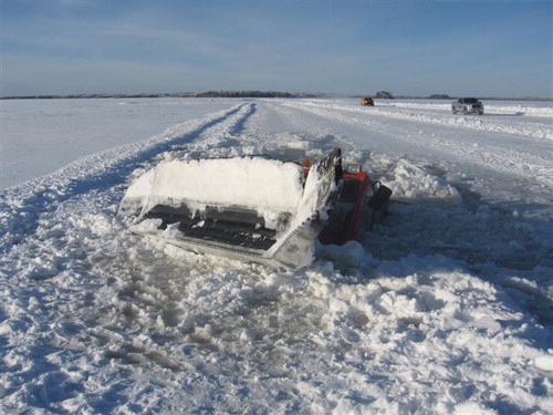 Figure 2. Snowplough fallen through the ice. Photo taken January 2011 between Sachigo Lake and Muskrat Dam, Ontario (west region). The absence and/or decreased depth of “blue-ice” formation are attributed to the reduction in the strength of the ice for winter road transportation. Source withheld; printed with permission.
