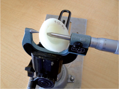 Figure 3. The cup wall thickness measurement setup showing the point micrometer, cup, and holding apparatus.