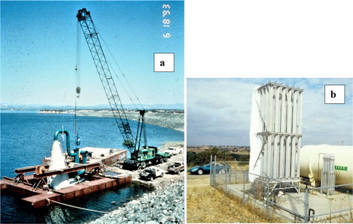 Figure 2. (a) Photograph of Speece cone assembly using a raft near the dam in June 1993. The white cone and green ancillary piping are shown, including T-shaped intake. The water pump is being lowered into the vertical piping. Several workers show scale. (b) Shoreline facilities; ∼10 m high evaporator and 50 m3 liquid oxygen tank; automobile shows scale.