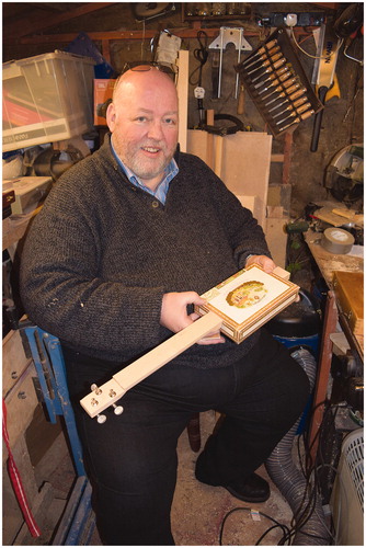 Figure 8 Nick Barney in his shed with a partly built three-string cigar box guitar.