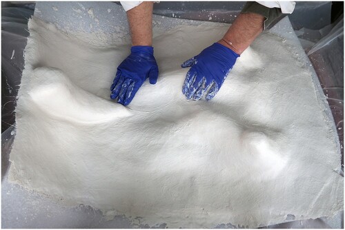 FIGURE 13. The feet have been plastered in place on the jacket, and the plaster surface is being smoothed before setting.