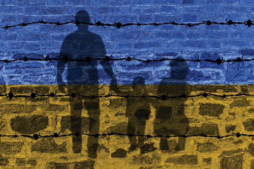 The shadow of a fleeing Ukrainian Family on the wall painted in the Ukrainian flag colors. (Courtesy: Shutterstock)