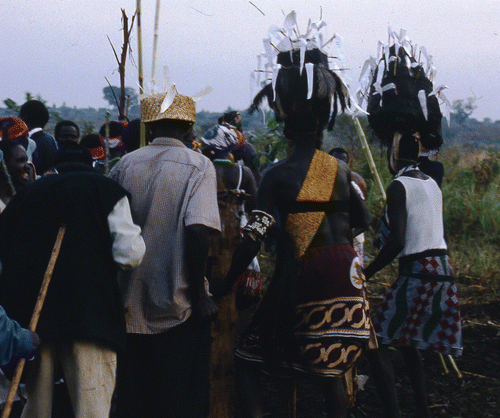 Figure 1 Sudanese Acholi elders wearing ceremonial headdresses made of wooden frame and plastic carrier bags dance at the funeral of an important ritual leader, taken by the author at the Kiryandongo Refugee Settlement, Uganda October 1997.