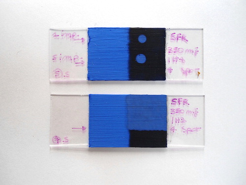 Figure 4. SFR, loosely-adhered dirt applied on the right side of the glass slides. On the upper slide, the two spots (the first with one pulse, the second with five pulses) were obtained with Fl = 1 J/cm2, E = 350 mJ, spot = 4 mm, f = 1 Hz. On the slide below we can see a cleaned part using the same operating parameters.