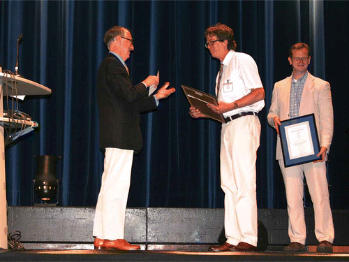 Figure 1. Geoffrey Luckhurst presenting the 2011 Luckhurst-Samulski Prize to Igor Muševič (centre) and one of his co-authors, David Wilkes (right) at the 24th International Liquid Crystal Conference held in Mainz, Germany.