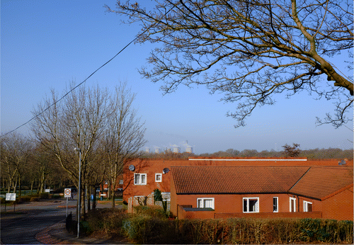 Figure 2. Windmill Hill is a densely built 1970s housing estate with pockets of woodland running through the estate, causing a discontinuity in the environment. This dark woodland is juxtaposed with tightly packed, dark, red brick houses. The uniformity of the planning reduces the sensorial texture of the space. In the background you can see the power station. A structure that can be seen from almost any vantage. This photo was taken from the top of the estate, which sits on a gentle slope. elderly residents at the bottom of the estate struggle to reach the shops, situated at the top of the estate due to the gradient. Photo: Gary Bratchford©.