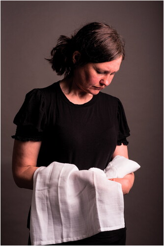 Figure 7 Lisa Porch holding, draping, cradling, and looking at the made object. Photo credit: Oliver Cameron-Swan.