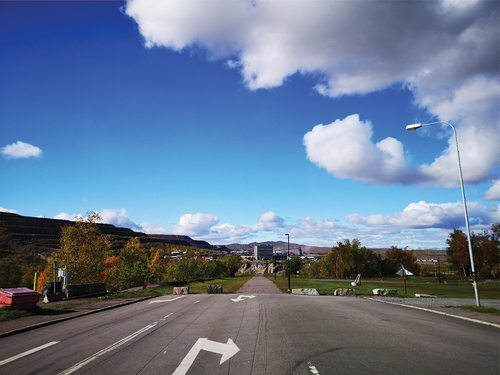Figure 1. Image of the E10, former main road, abruptly turning into a footpath. In the background of the image can be seen the office buildings of LKAB, sitting above the former open-pit on Kiruna’s western margin. Photo by author, September, 2020.