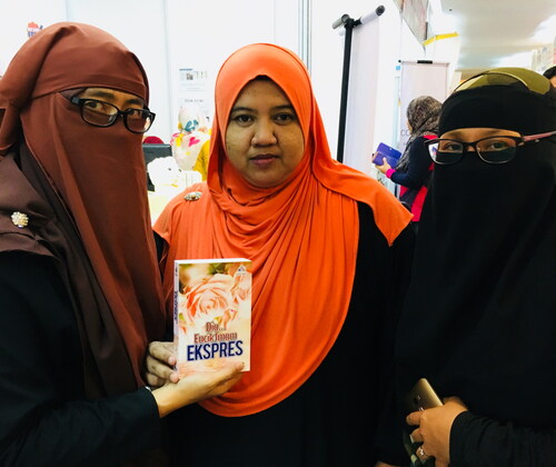 Figure 3. Cik Tet (centre), a bestselling romance author, seen here flanked by her fans at the 2018 Kuala Lumpur International Book Fair. Photograph by the author.