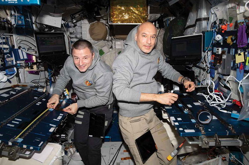 Figure 1. Astronauts Andrew Morgan and Luca Parmitano dressed in hooded sweatshirts in the microgravity environment of the International Space Station. Due to weightlessness the sweatshirts billow away from the body, with hoods rising upwards towards the wearers’ heads, and fabric distorting at the chest where it is out of contact with the body. NASA, 2019