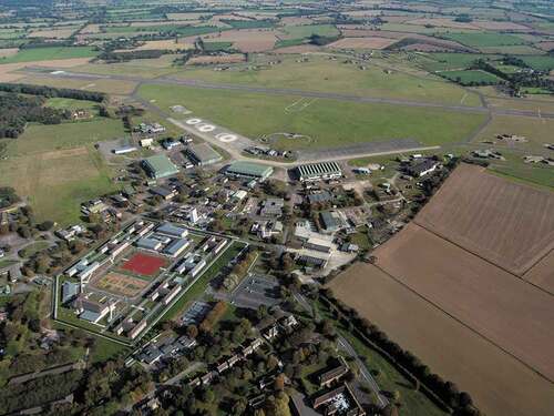 Figure 1. Aerial photograph of HMP Bure, formerly RAF Coltishall. The prison comprises the cluster of original military buildings (including H blocks) at bottom left, enclosed within a new perimeter wall, and centred around the original parade ground (now a sports field). Military aircraft hangars and the airfield itself are clearly visible, beyond the prison complex, at the top and centre.