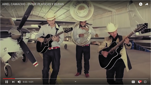 Figure 9. The late Ariel Camacho plays with his group Los Plebes, an example of a sierreño-Banda, in an airplane hangar for the video Entre platicas y dudas (2014). C. Del Records, Inc. Posted on Youtube by Ariel Camacho.