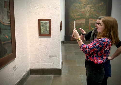 Figure 7. Documentary photograph of the app test. Test persons are using the app in the exhibition, in front of the portrait painting of Eva Arosenius.