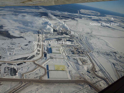 Figure 6. Aerial photo showing dispersion of plumes from Suncor base plant and Syncrude Mildred Lake. In winter, the condensing of the water vapor in emission allows a visual observation of the dispersion patterns of different emission sources. Suncor Base Plant’s flue gas desulfurization stack is 137 m high and has a base level of 255 m, whereas Syncrude’s main stack is 183 m high and has a base level of 304 m. Thus, emissions from Suncor’s stack are often trapped in the Athabasca Valley and subject to the predominant north-south valley winds, whereas Syncrude’s emissions (B) may escape this ground-level wind pattern. Photo: Ryan Abel.