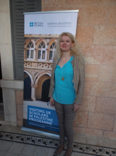 Dr Beverly Butler at Riwaq in Ramallah standing by the Visiting Scholars in Palestine banner