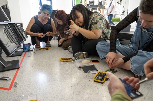 Figure 5. Suzon Fuks (Australia) and participants taking computer hard drives apart. Photo by David Kumermann; Prague Quadrennial 2023.