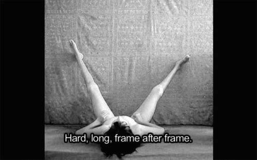 Figure 1. Still frame showing a black and white photograph of sachse lying on their back with their legs raised against a backdrop. A caption reads ‘Hard, long, frame after frame’. From Body Language by jes sachse.Footnote4