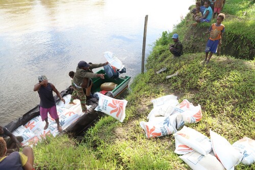 Figure 4. Village Head of Sinimburu (left), throwing ashore ‘Welfare Rice’, September 2017. The motorboat was also village aid.
