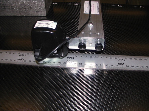 Figure 1.  Experimental set-up for the longitudinal measurements on Ac4 with the 2000 mm ruler aligned on the table top. The black housing is the USB-microscope from Spectrum Technologies, Inc. The 8 cm aluminium arm was mounted via two thumbscrews at the end of a 25×50 mm2 massive aluminium bar of length 124 cm (weight 4.2 kg). A PTW MP3 water phantom was used as elevation stage for aluminium bar with the microscope mounted at the end.