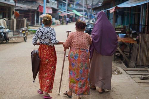 Figure 1. Three women make their way to the market in Myeik, lending support to the older woman walking in the middle (photograph by Samia C. Akhter-Khan).