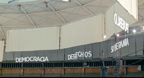 Figure 2. Highly charged signifiers such as democracia, derechos, soberanía, and pueblo hang from the rafters in the 2014 Vistalegre Assembly. Image reproduced with the permission of Mediapro.