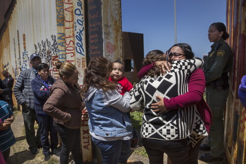 Figure 7. Griselda San Martin, The Wall, 2015–16. Gabriela Esparza (in red) reunites briefly (3 min) with her sister Susana and her mother María del Carmen Flores during the “Opening the Door of Hope” event at the border wall in Playas de Tijuana, Mexico, on April 30, 2016. On January 2018, Border Patrol announced the door will not re-open. Photograph © Griselda San Martin.
