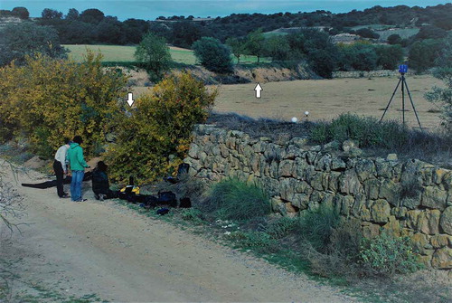 Figure 3. Fieldwork on the Balaguer-Castelló road (looking north-west). Arrows indicate the location of profiles taken from the stone-faced check-dam in the foreground and the earth bank in the background, which delimits the gently-sloping terraced field behind. Photo: Sam Turner, November 2014.