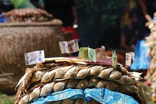 Figure 1. Kina notes, banana leaf bundles (doba), and calico cloth prepared for distribution at a mortuary feast (sagali) in a kind of payment called sepwana. Source: Photo by author.