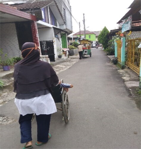 Photo 4. A photo of Participant 1 on a wheelchair and his carer. Participant 1 usually passed concrete roads in his weekly morning outing. The concrete roads had flat surfaces which improved comfort for wheelchair users..