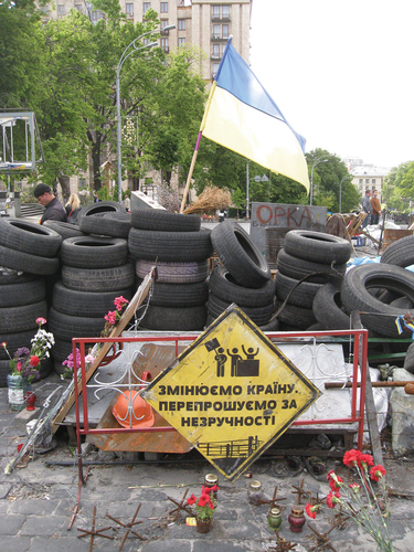 Figure 6. A “commemorative” barricade on the upper part of Instytutska Street as it existed in the summer of 2014. The sign reads “Changing this country. Apologies for the inconvenience.” Author’s photo.