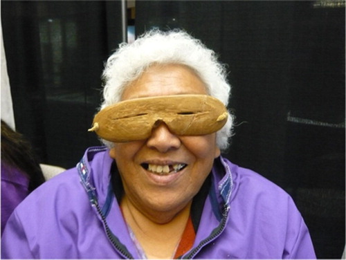 Fig. 3 Picture showing an elderly Alaskan Inuit woman demonstrating her traditional “sunglasses” at the 15th International Congress of Circumpolar Health held in Fairbanks in August 2012. Similarly, eye protection from sealskin was known to be necessary to Inuit hunters in Greenland during spring and summer (Citation33).