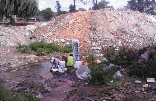 Figure 8. Residents washing paint containers in the stream next to a dumping area.Source: Author’s Photograph, November 2014.