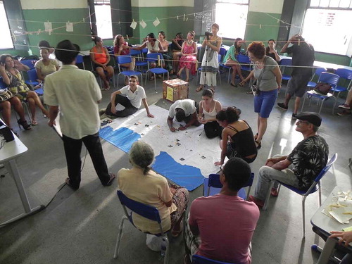 Figure 2. ‘Dreams, Propositions and Projects Workshop in 2 de Julho, Salvador, 2014’. The second workshop focused on the dreams, proposals and projects of residents, state and private initiative, for the neighbourhood. A large map was used for the residents to locate their dreams and propositions for the neighbourhood, identifying also their agents. This workshop was held in the neighbourhood public state college ‘Colégio Estadual Ypiranga’ on 26 April 2014. Photo by Camila Brandão.