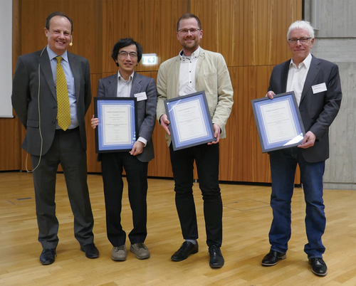 Figure 1. (Colour online) Corrie Imrie presenting the 2021 Luckhurst-Samulski Prize to Atsutaka Manabe, Martin Kraska and Matthias Bremer at the 49th German Liquid Crystal Conference held in Stuttgart (March 2023).